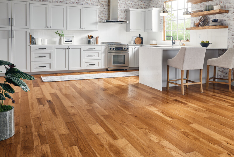 All white kitchen with an island and light-toned, multi-colored hardwood flooring